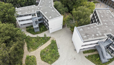 Vogelperspektive auf den neugestalteten Schulhof der Stadtteilschule am Hafen mit Schulwald, entsiegelten Grünflächen und Retentionsmulden